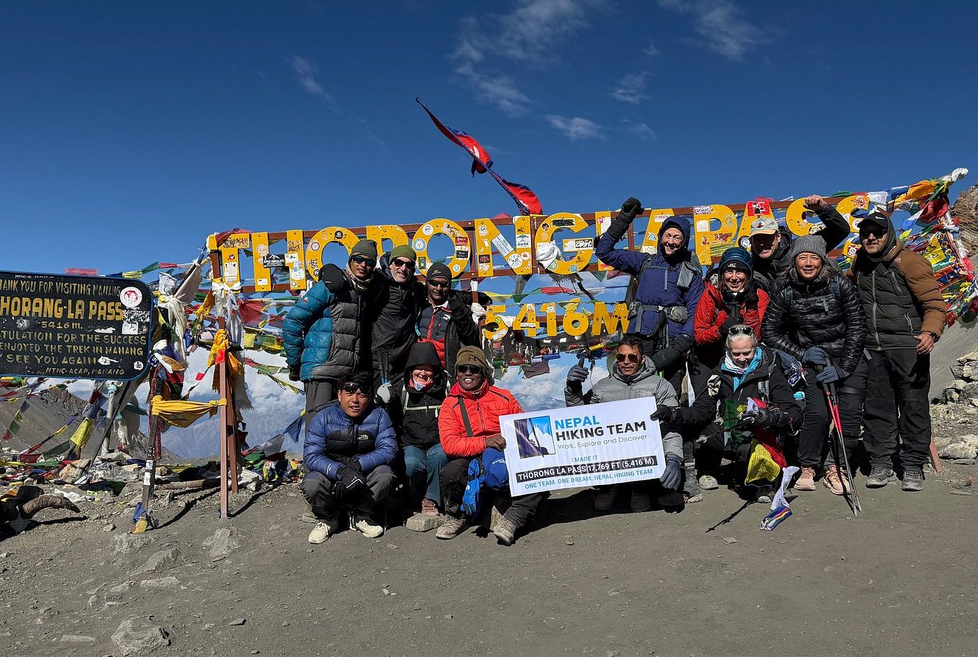 Trekking group celebrating at Thorong La Pass 5416m on the NATT Annapurna Circuit Trek Nepal