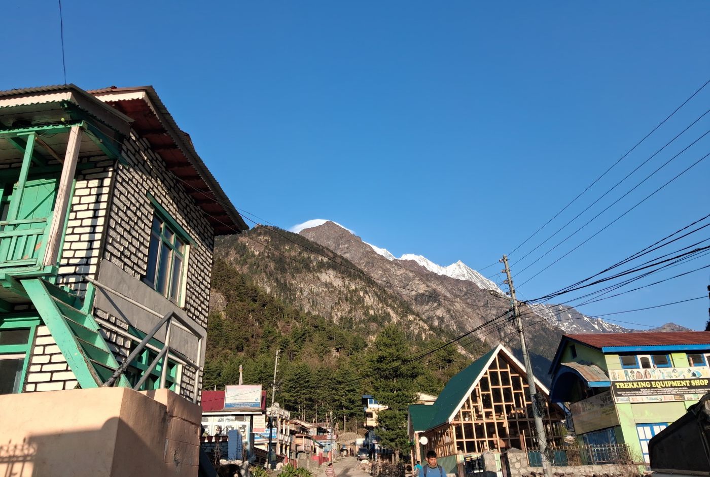 Main street in Chame with trekking equipment shop and mountain backdrop on the Annapurna Circuit