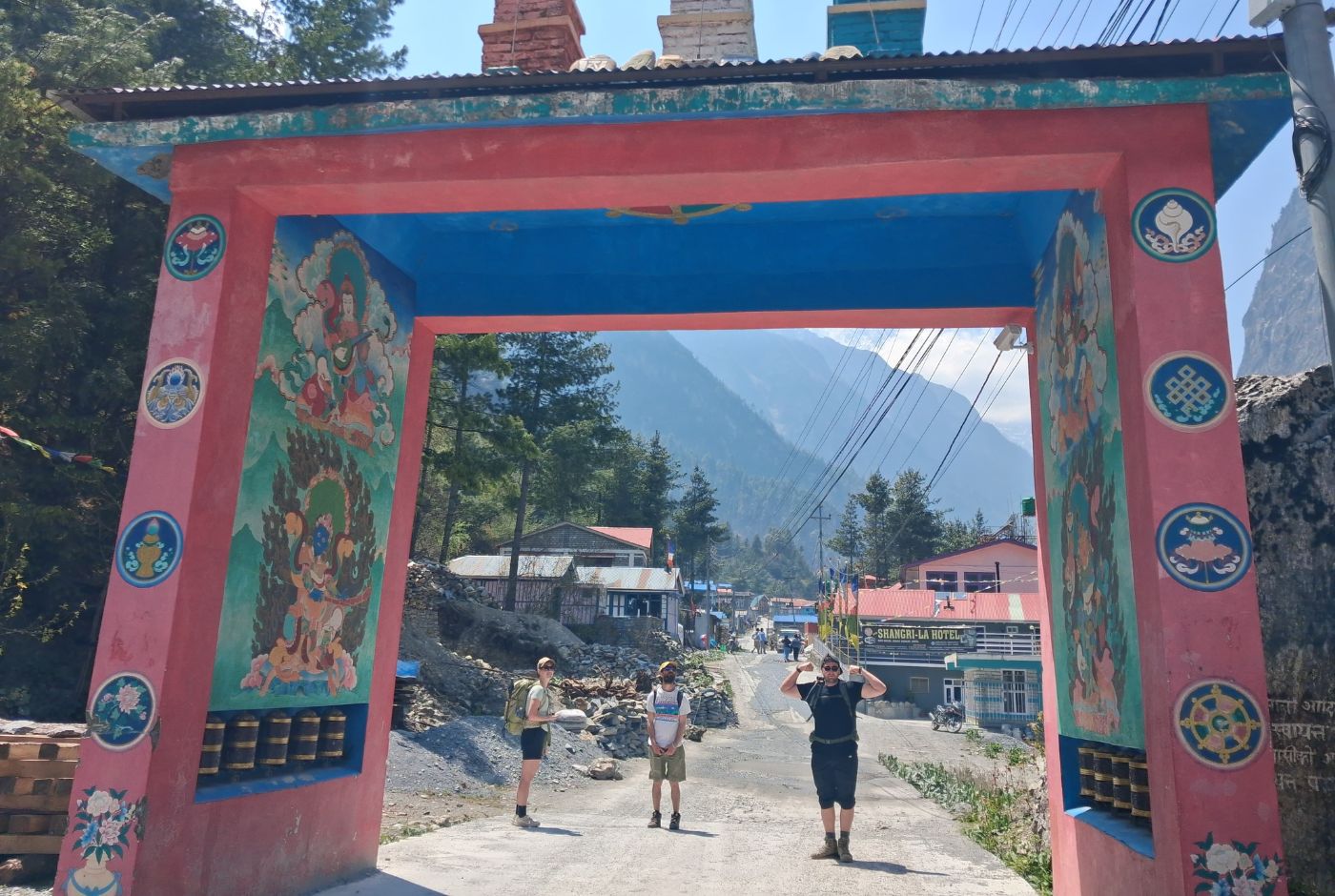 Trekkers arriving beneath the painted entrance arch in Chame on the Annapurna Circuit