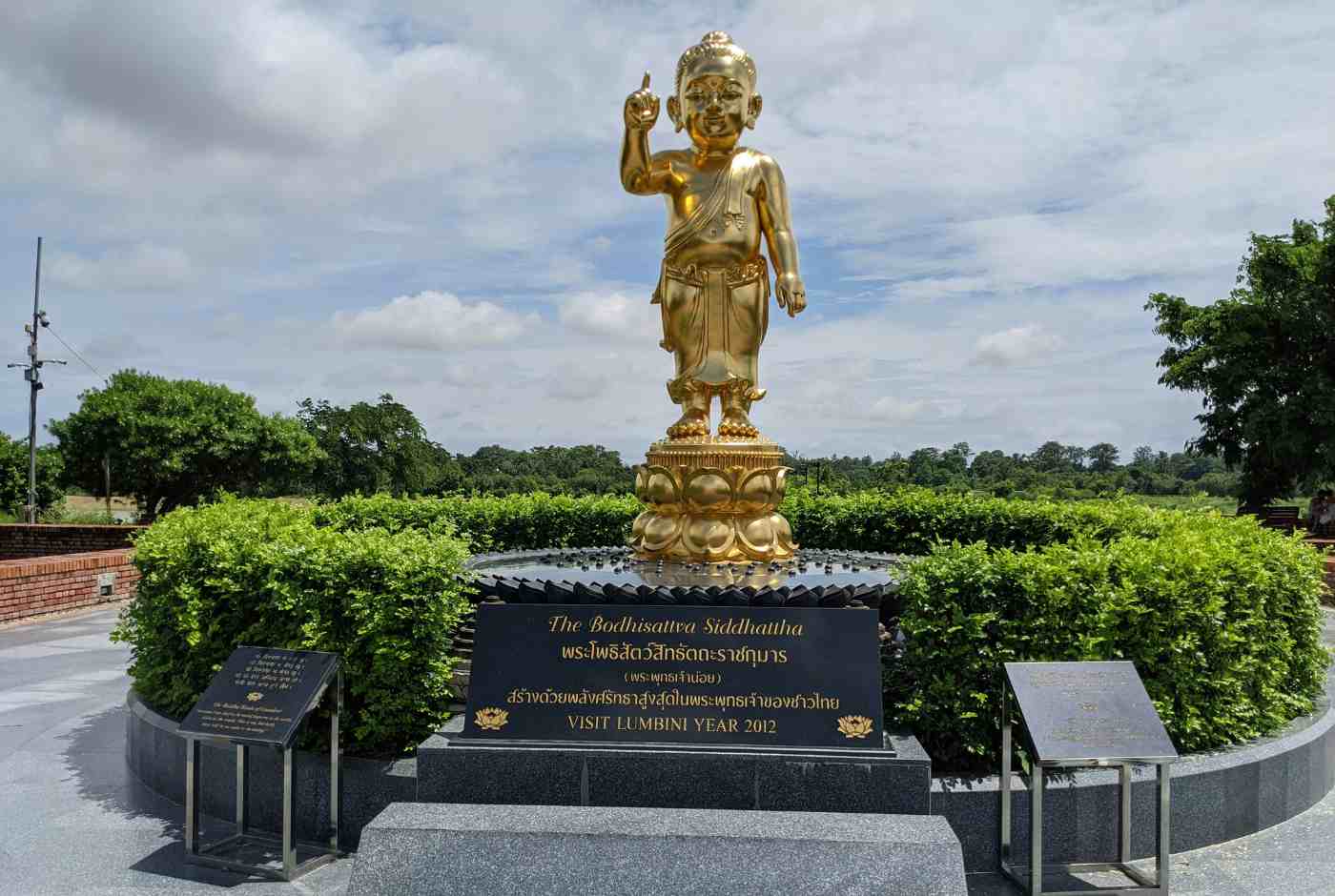 Golden Buddha statue in Lumbini Nepal garden symbolizing peace and spiritual presence