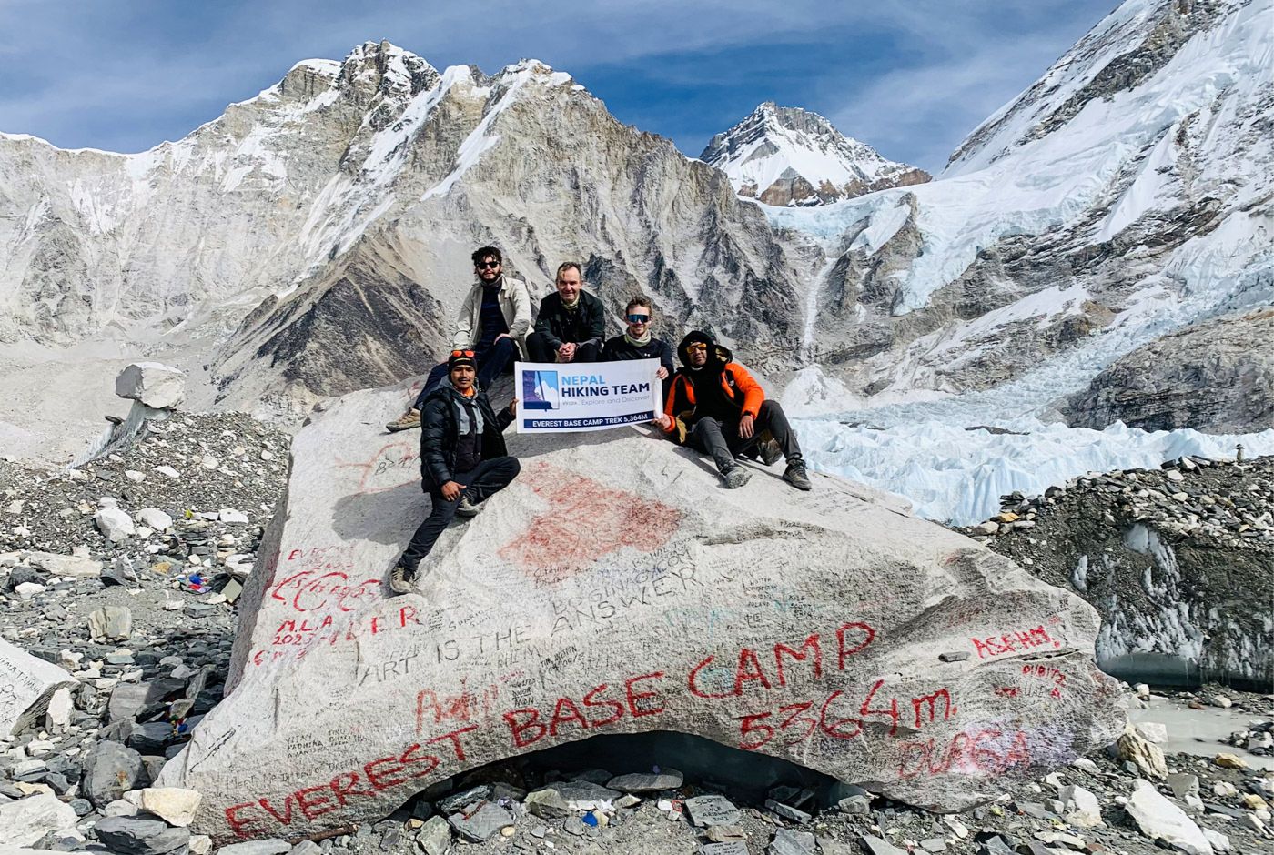 Trekkers at Everest Base Camp sign at 5,364 meters, Nepal, with proper travel insurance coverage