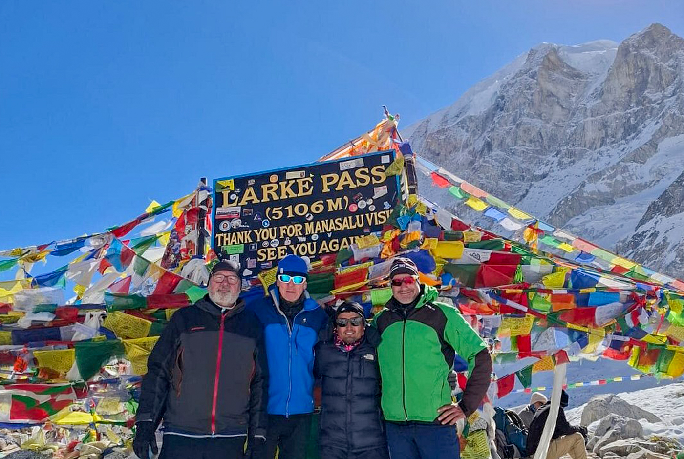 Group of trekkers celebrating at Larkya La Pass 5160m sign on the Manaslu Circuit Trek Nepal