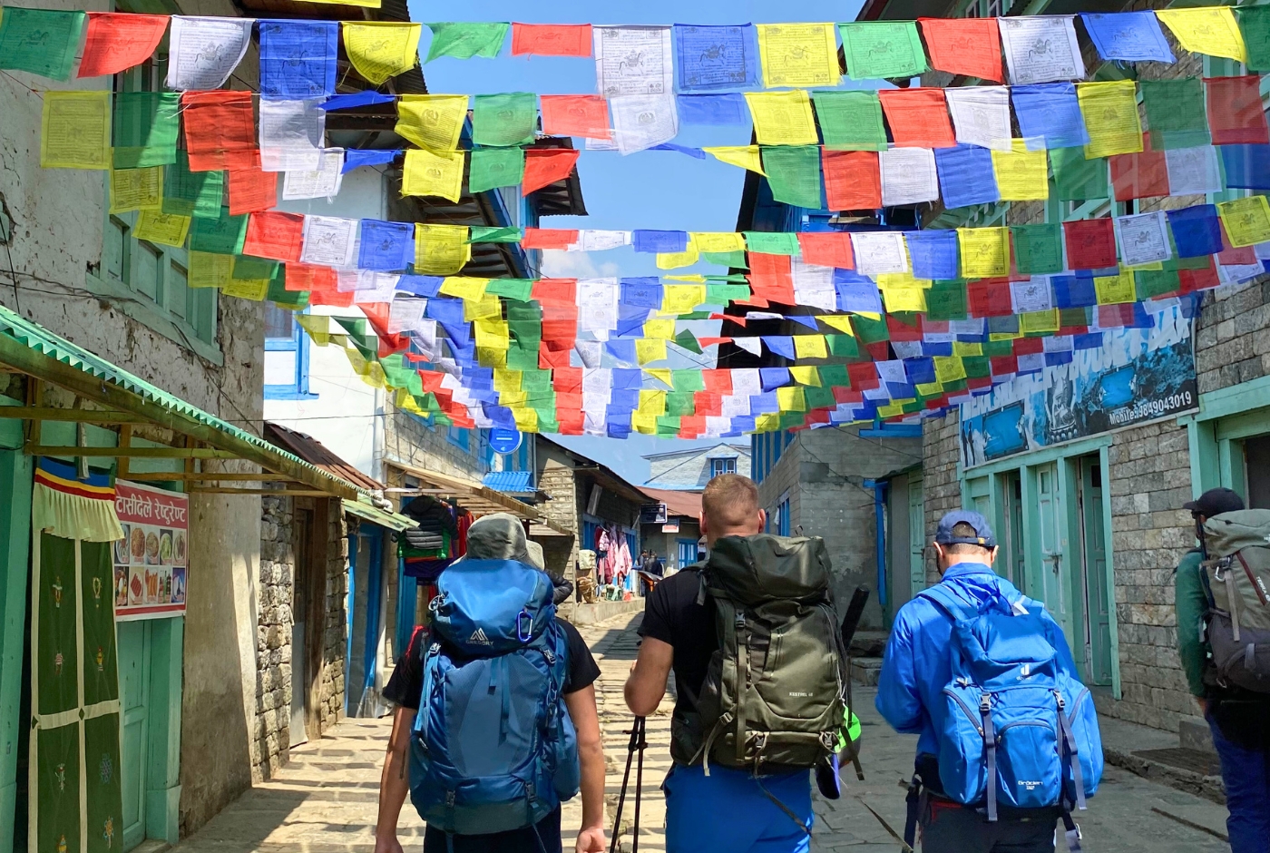 Trekkers walking through Lukla village under prayer flags in the Everest region