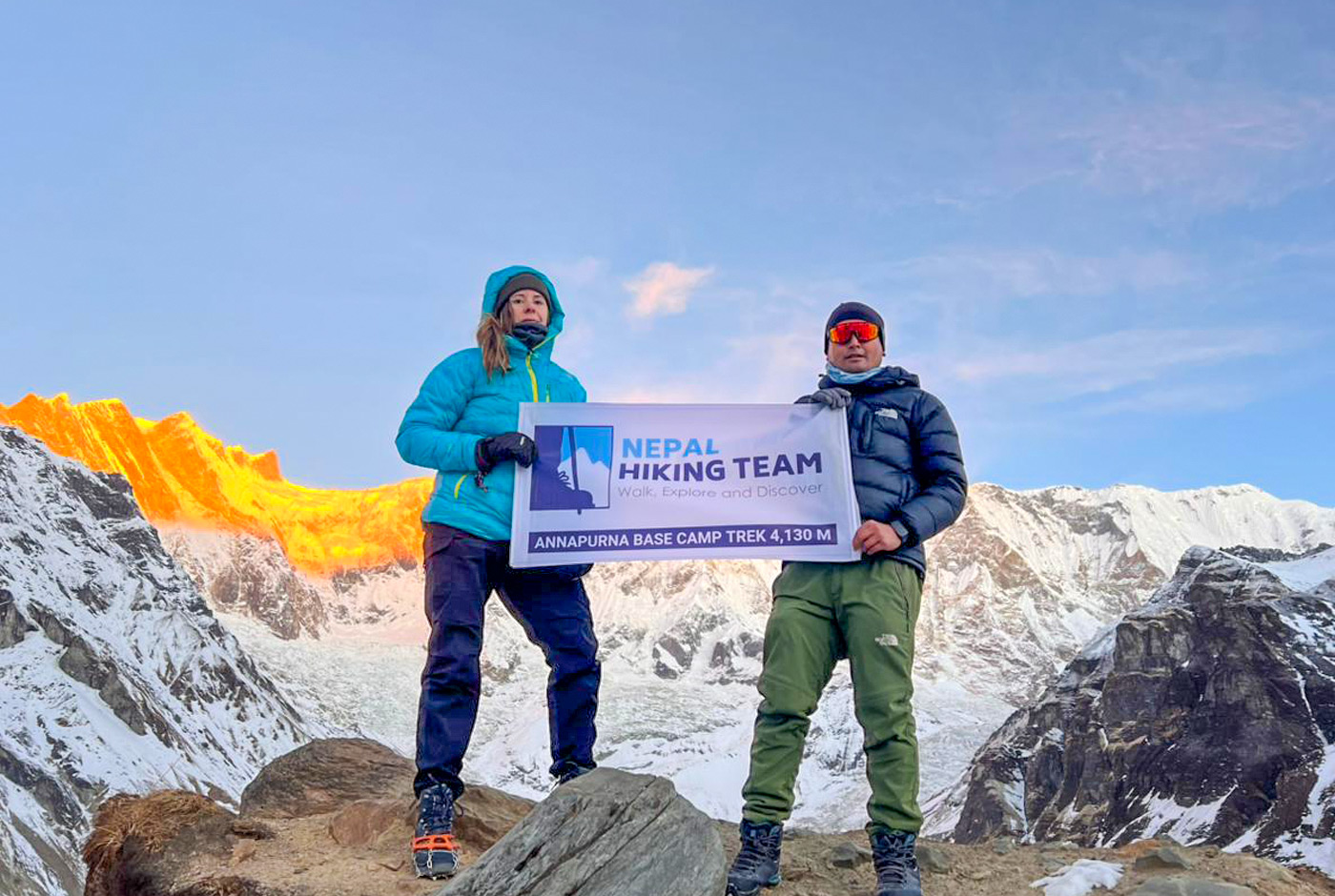 Nepal Hiking Team guide and trekker at Annapurna Base Camp 4130m with snowy peaks behind them