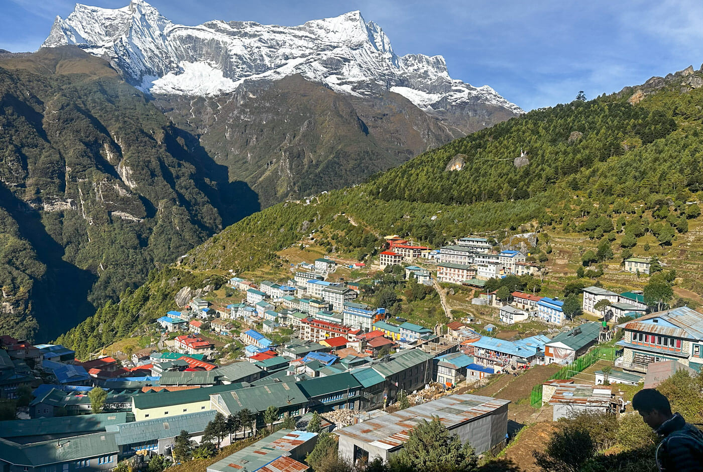Namche Bazaar village with colorful teahouses and lodges nestled on Himalayan mountainside with snow-capped peaks above
