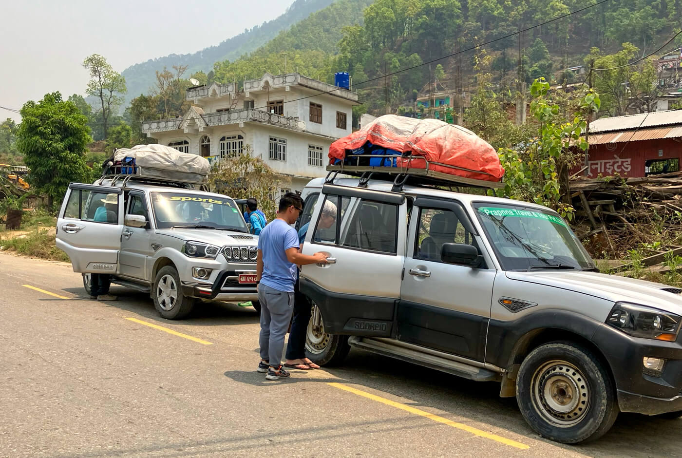 Two Mahindra Scorpio 4x4 jeeps with luggage strapped to the roof racks on the road