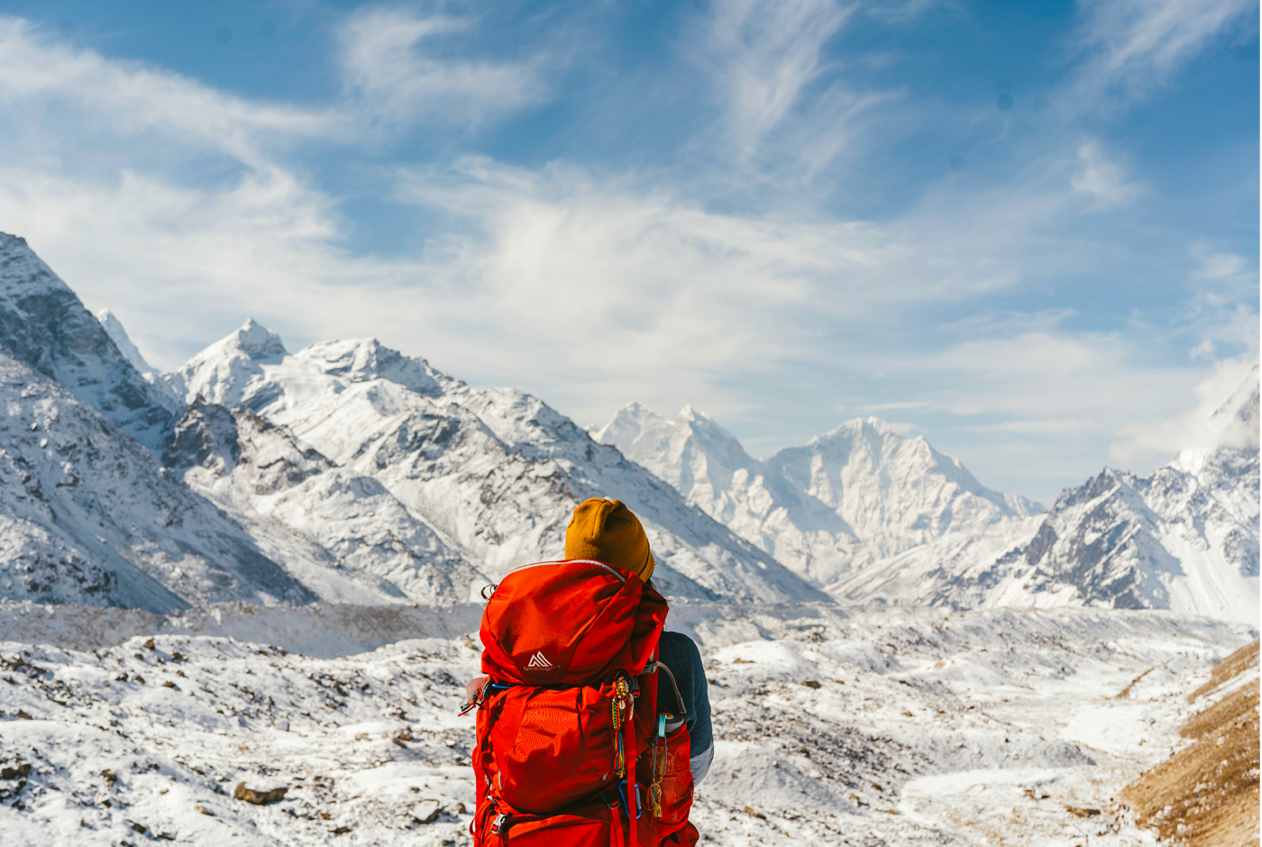 Hiker overlooking snow covered Mountain Peaks