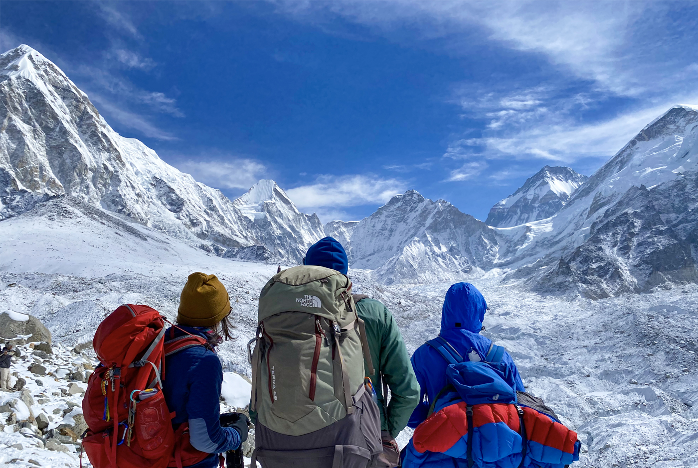 Three hikers with backpacks on Everest Base Camp trek-overlooking snowcovered-Himalayan