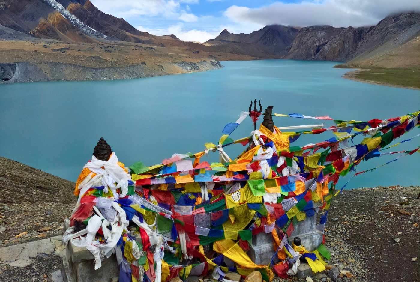 Tilicho Lake with prayer flags and statues, surrounded by mountains in Nepal