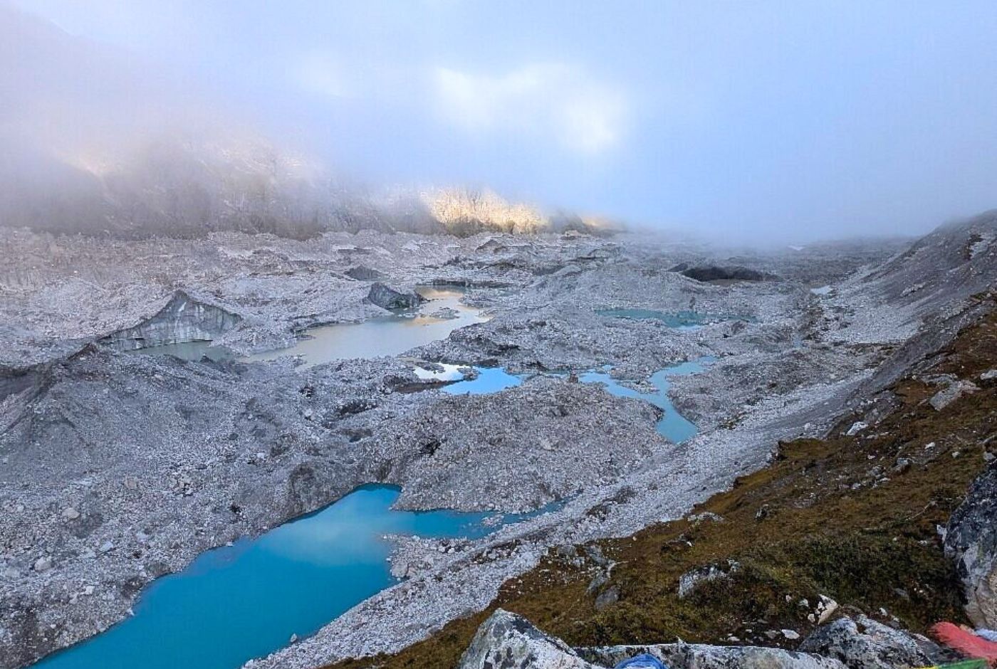 Turquoise Gokyo Lakes surrounded by Ngozumpa Glacier moraine and teahouses in Everest region at 4700 meters